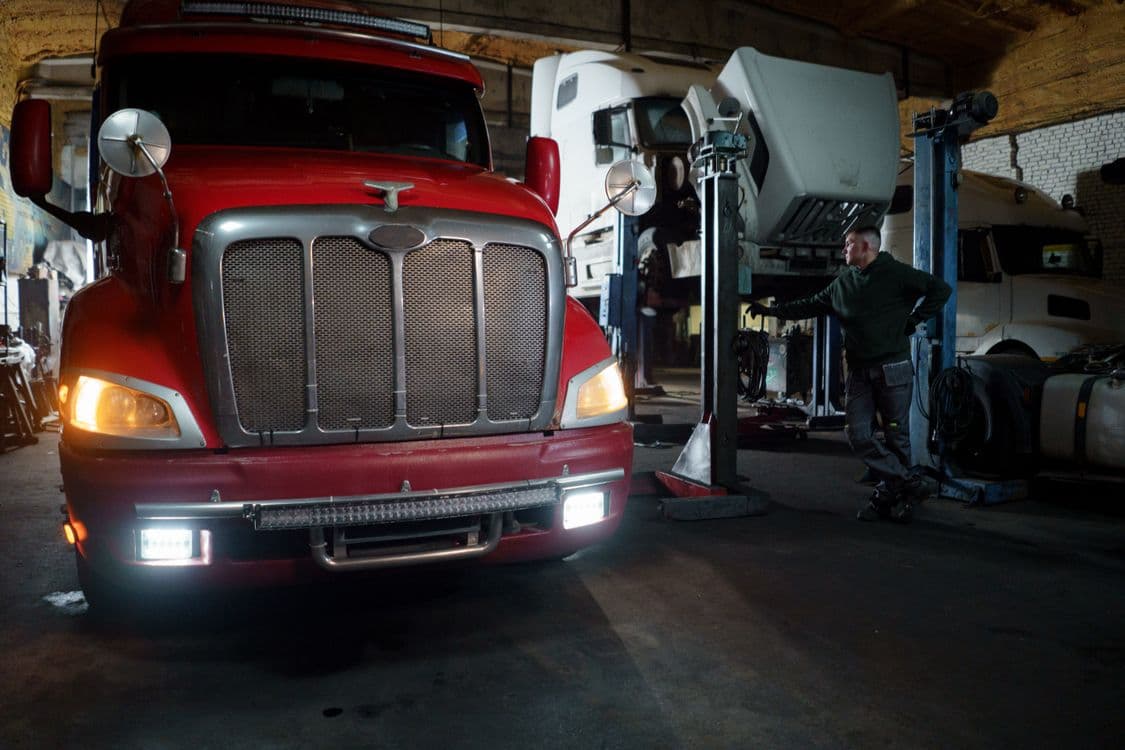 Mechanic and red semi-truck inside a repair workshop