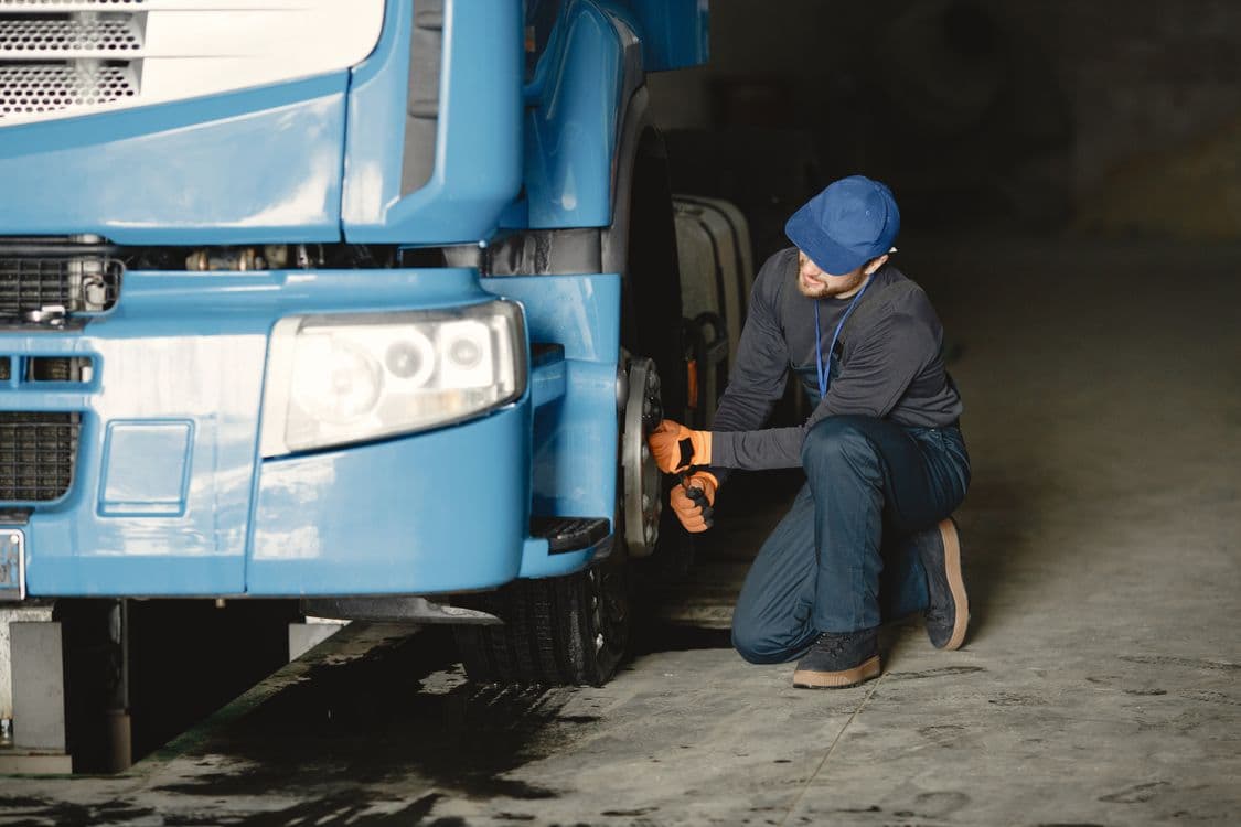 Mechanic repairing the wheel of a blue commercial truck