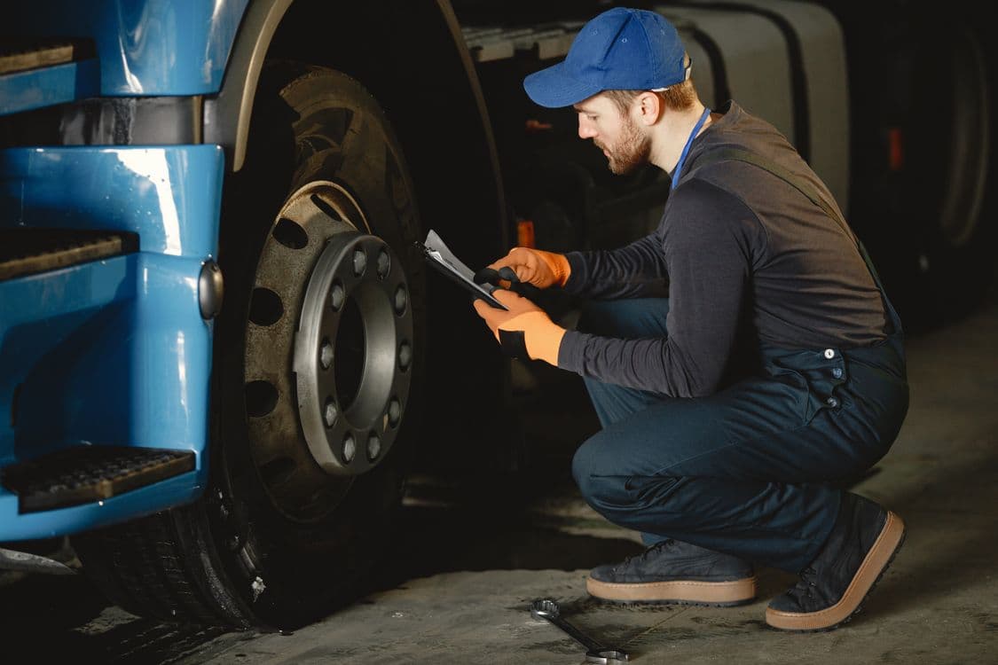 Technician checking a commercial truck wheel during a DOT inspection